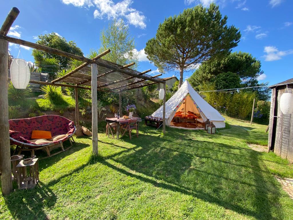 Wide shot of lounge area and lotus glamping tent with a big patch of green grass