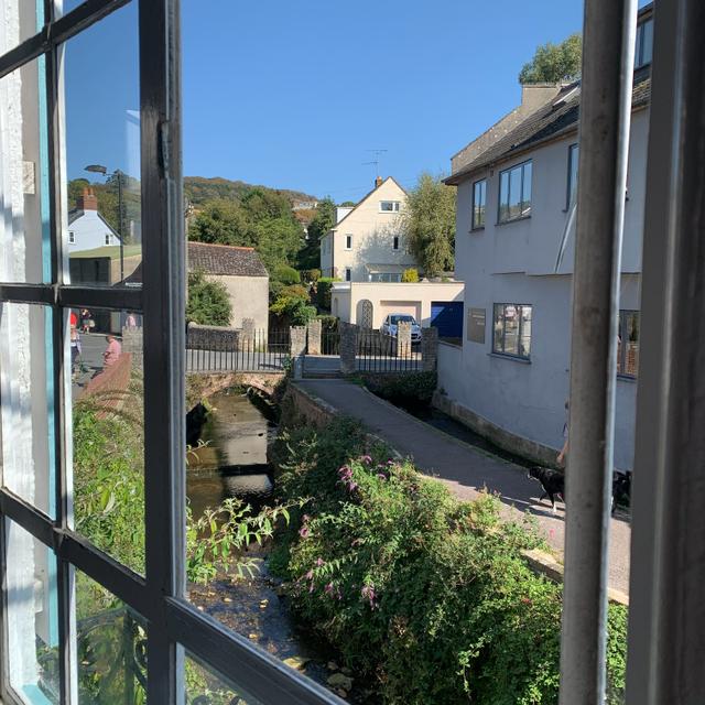 View to river below from the dining and living space window through these period framed windows of what was an old mill looking out onto the river Lym and the 18th century Gosling Bridge in central Lyme Regis  Dorset