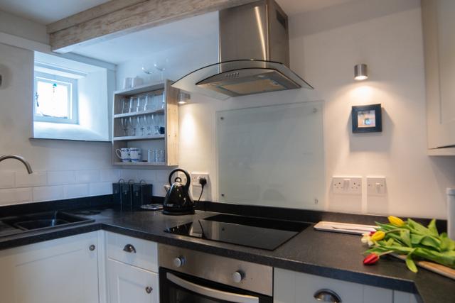 Through the wooden clad statement doorway into the galley kitchen of this boutique holiday cottage with luxury interiors and contemporary kitchen design