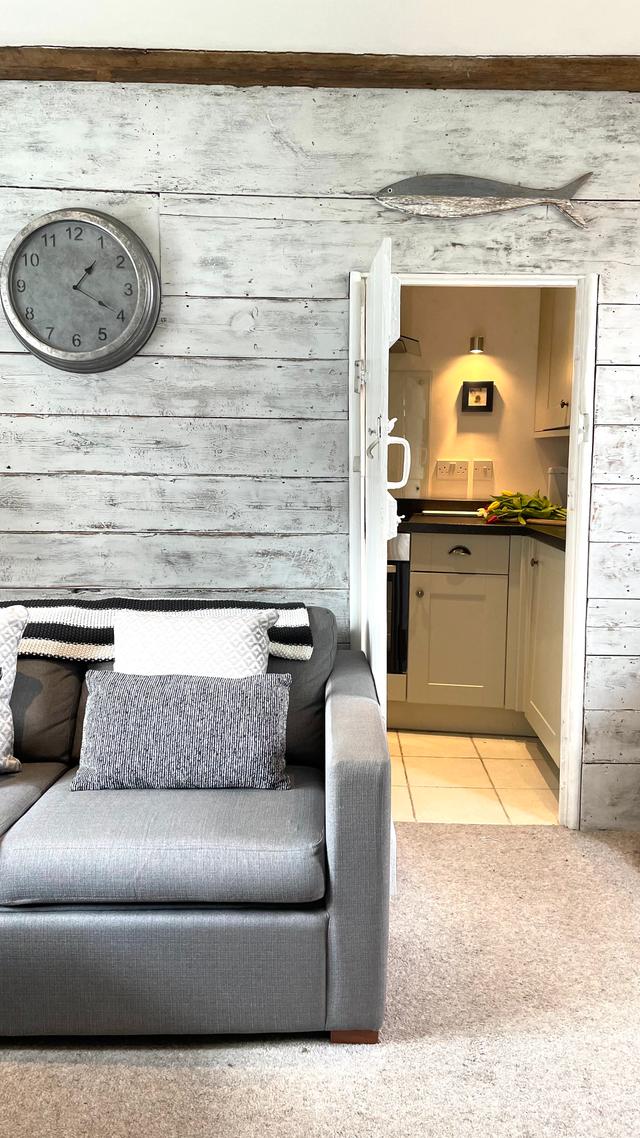 Cosy sitting room lounge with views of the river, stylish interiors both contemporary and period features with the most charming doorway into the galley kitchen of this holiday cottage