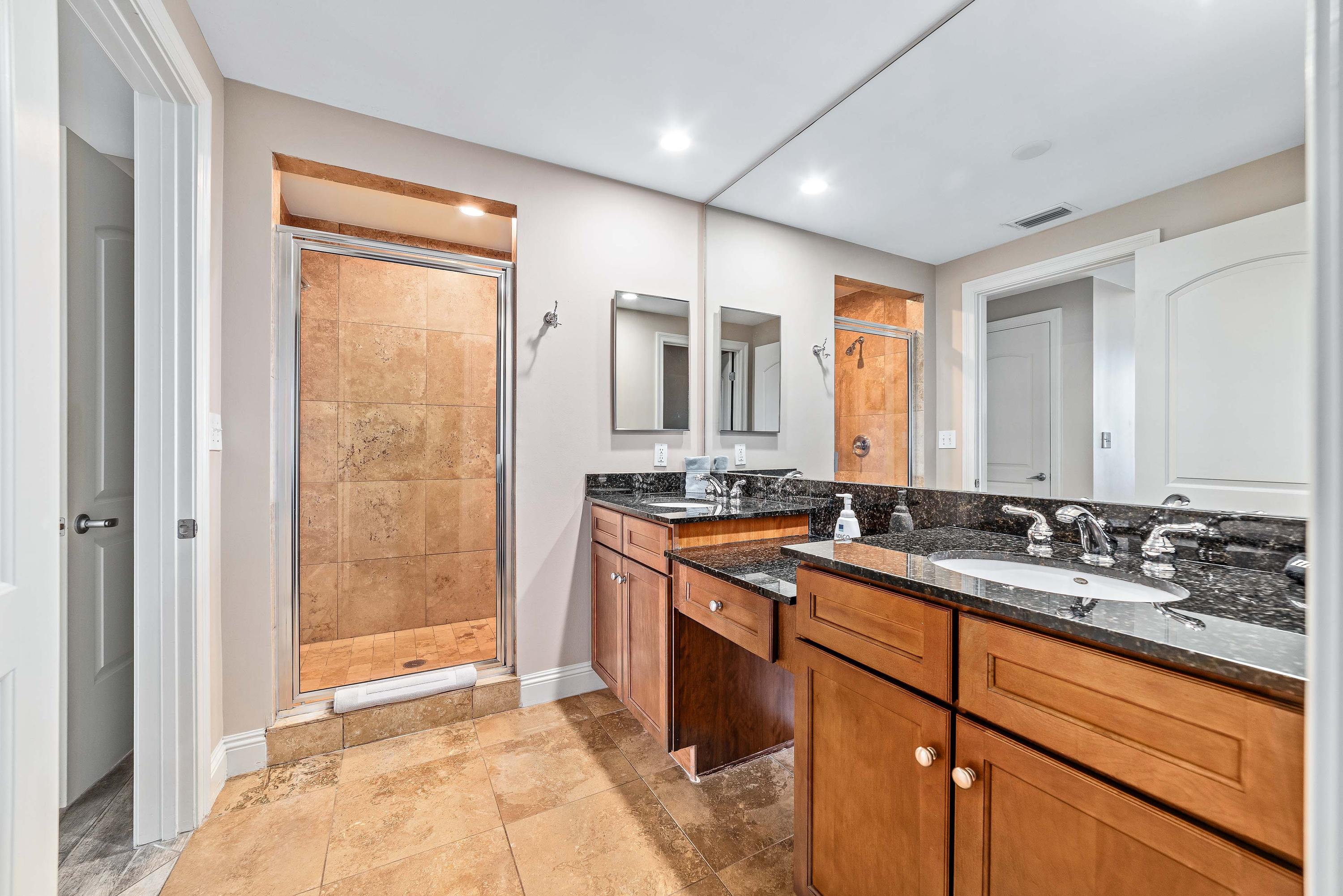 Spacious master bathroom with dual granite vanities, walk-in Travertine shower