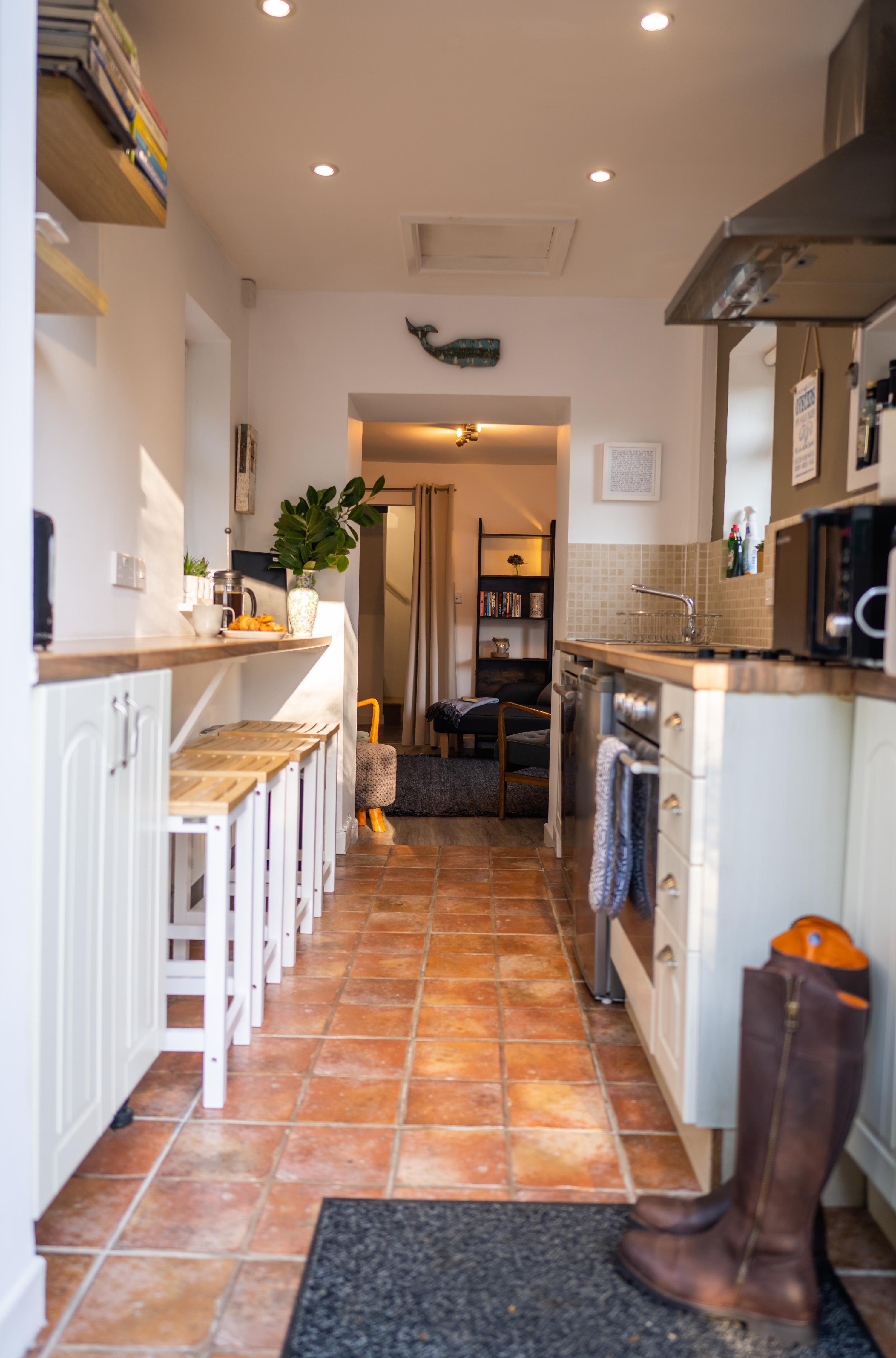 Fisherman's galley kitchen with stools and bench kitchen seating with views through to contemporary lounge