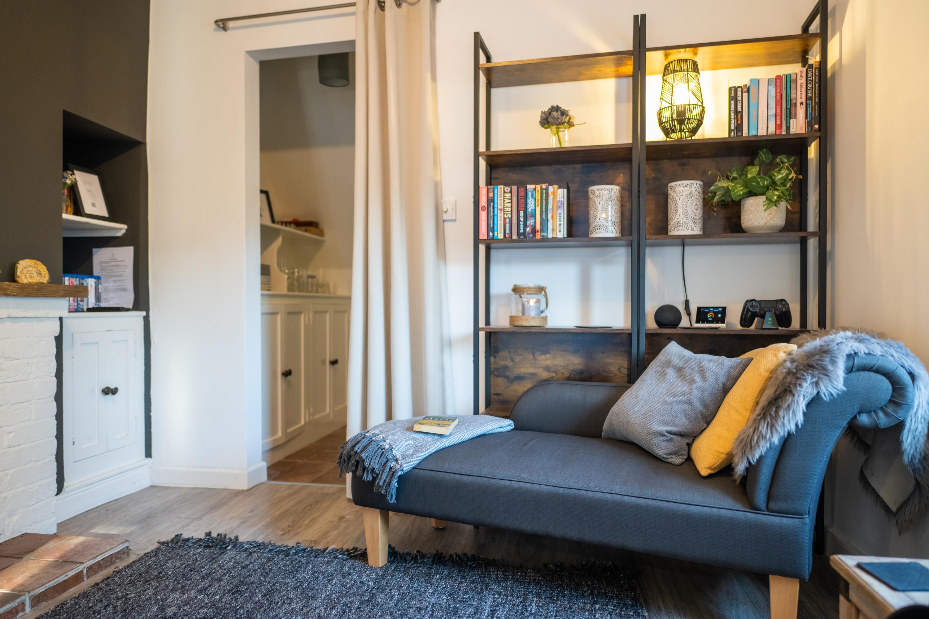 Chaise longue in the lounge with book shelves and entrance to hallway at this characterful period cottage whihc is over 200 years old