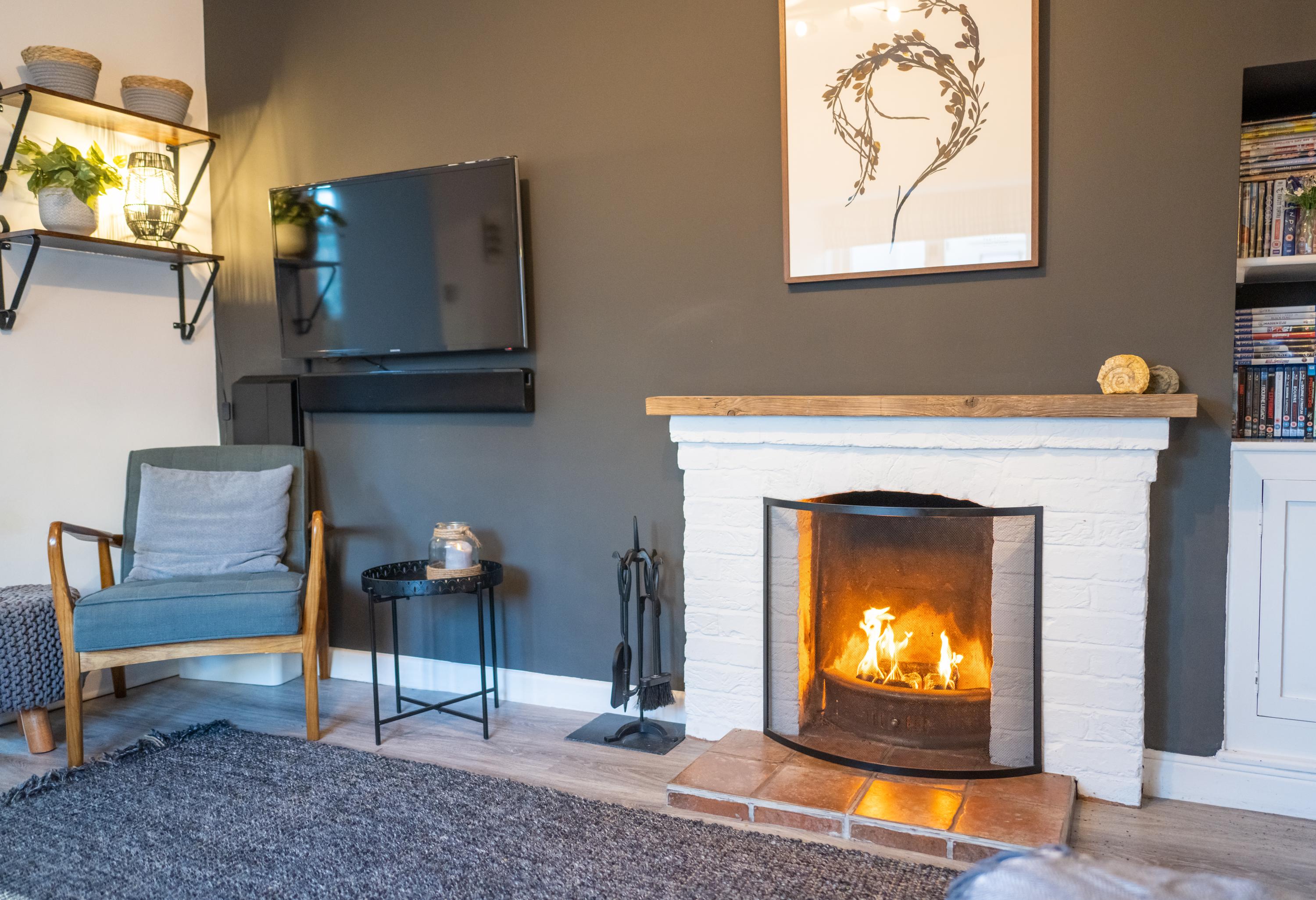 Fireplace with open fire artwork large wall mounted TV and easy chair in the lounge overlooking the river