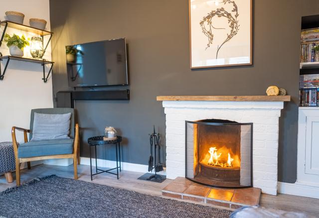 Fireplace with open fire artwork large wall mounted TV and easy chair in the lounge overlooking the river