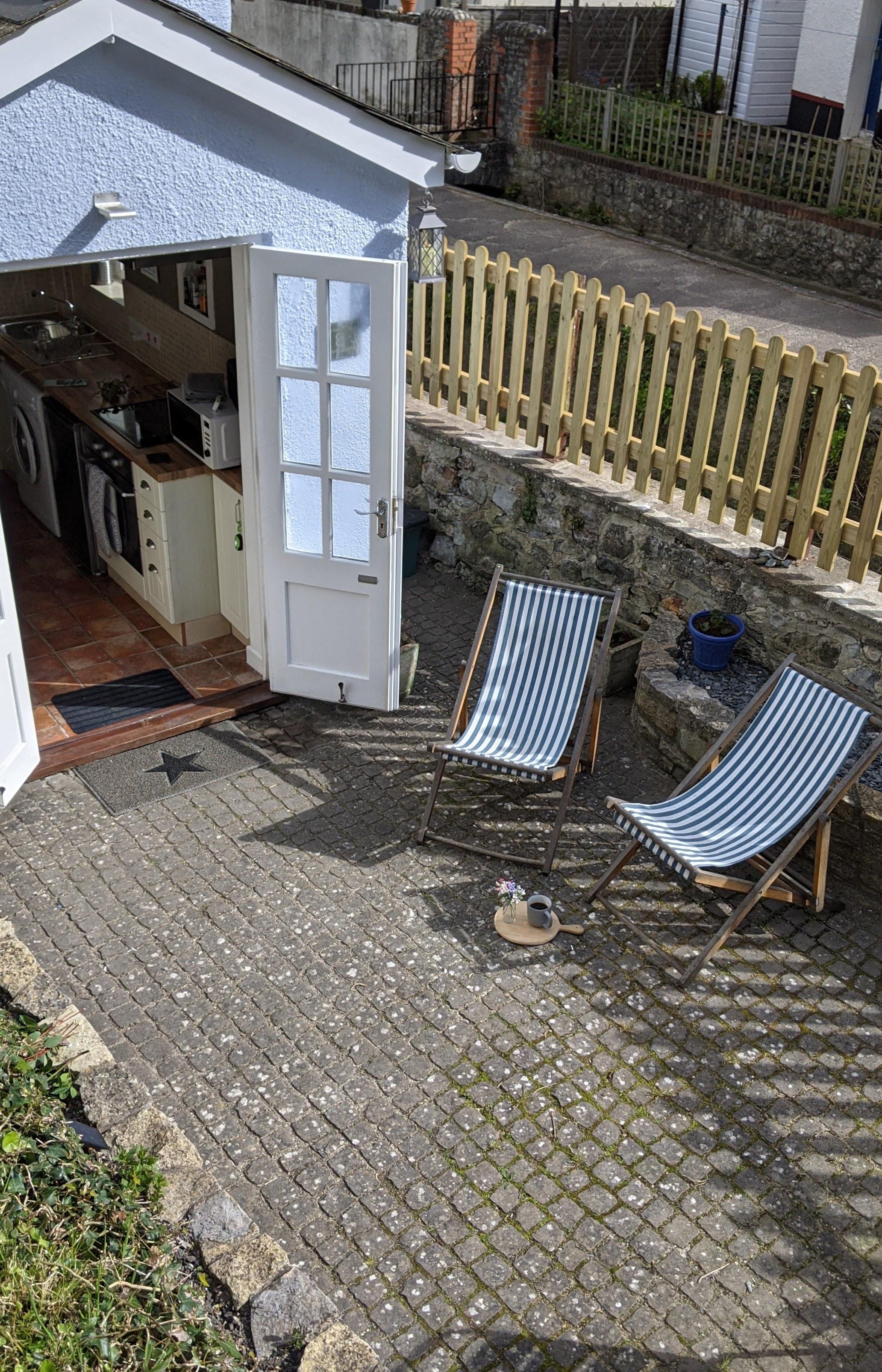 Courtyard with deck chairs opening into the kitchen via french doors and over looking the River Lym with river views