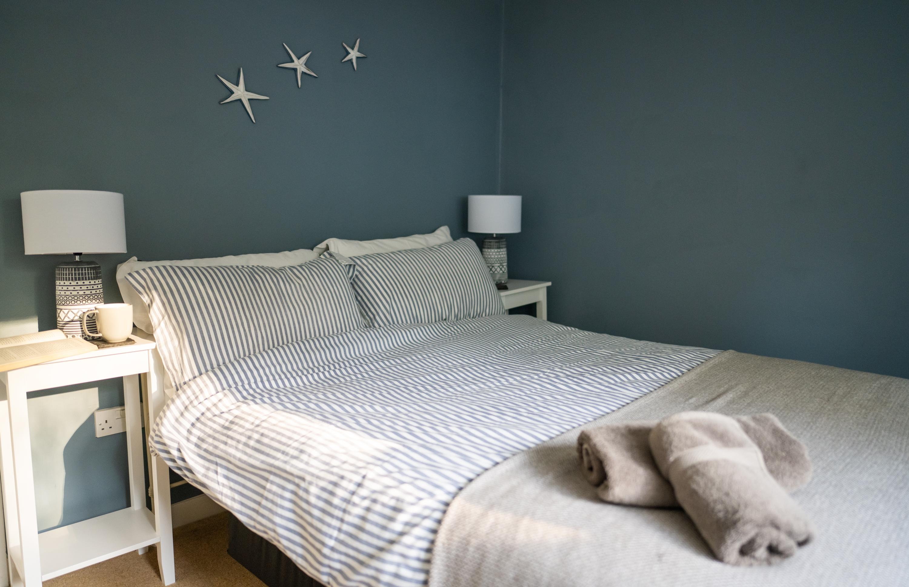 Double bedroom with mineral paint coloured walls, bedside tables and lamps at Lynch View Cottage in central Lyme Regis