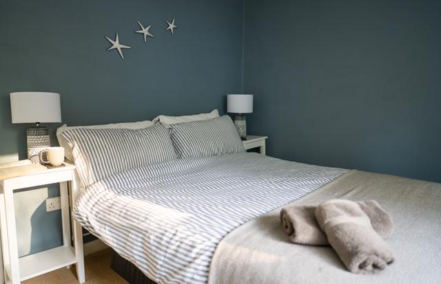 Double bedroom with mineral paint coloured walls, bedside tables and lamps at Lynch View Cottage in central Lyme Regis