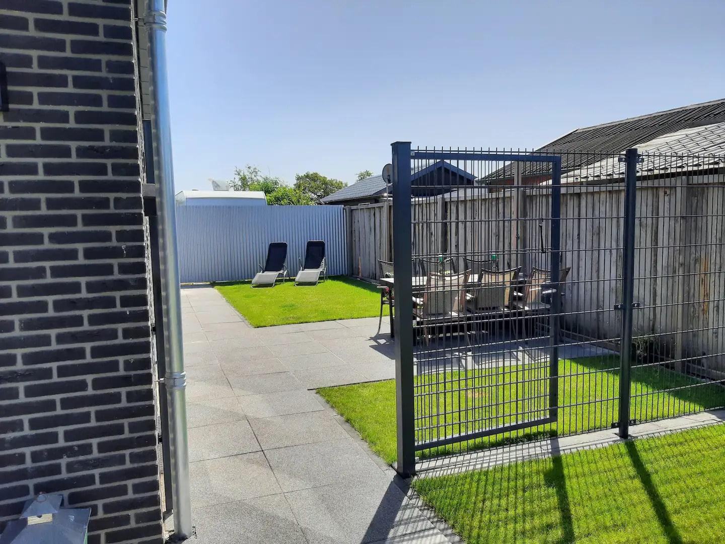 De afgesloten tuin met houten beschutting en stalen hekwerk (1,80m hoog)