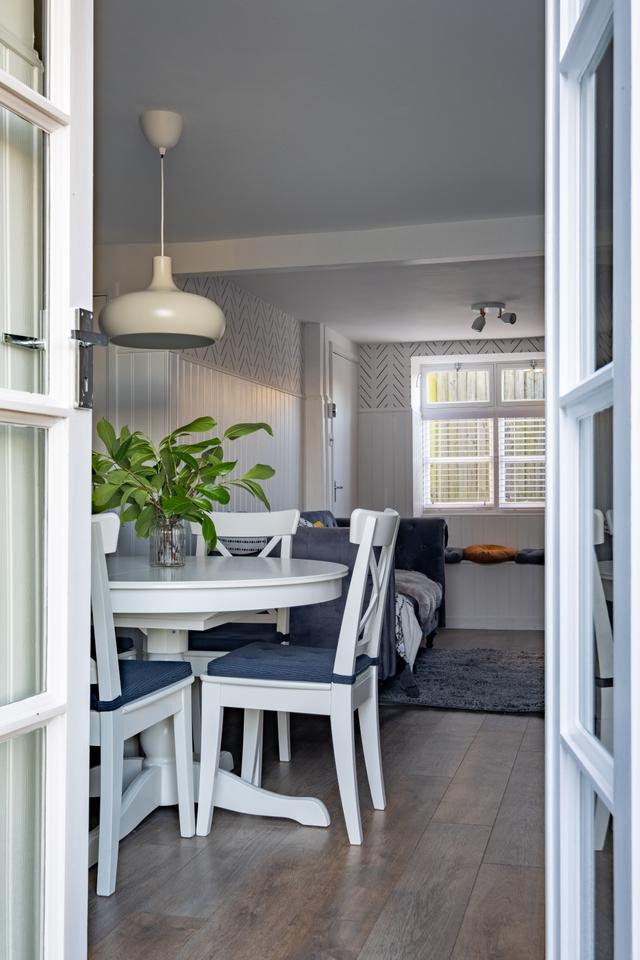 French door entrance from garden into this characterful holiday cottage showing cnetral round table with over head light sofa and coffee bar 