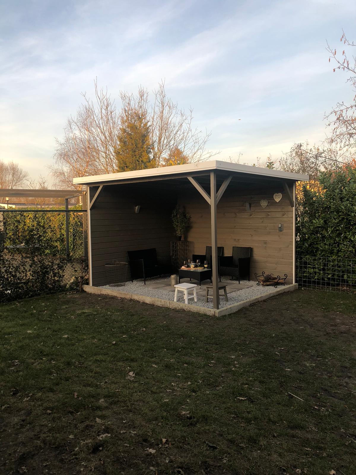 Het overdekte terras in de omheinde tuin