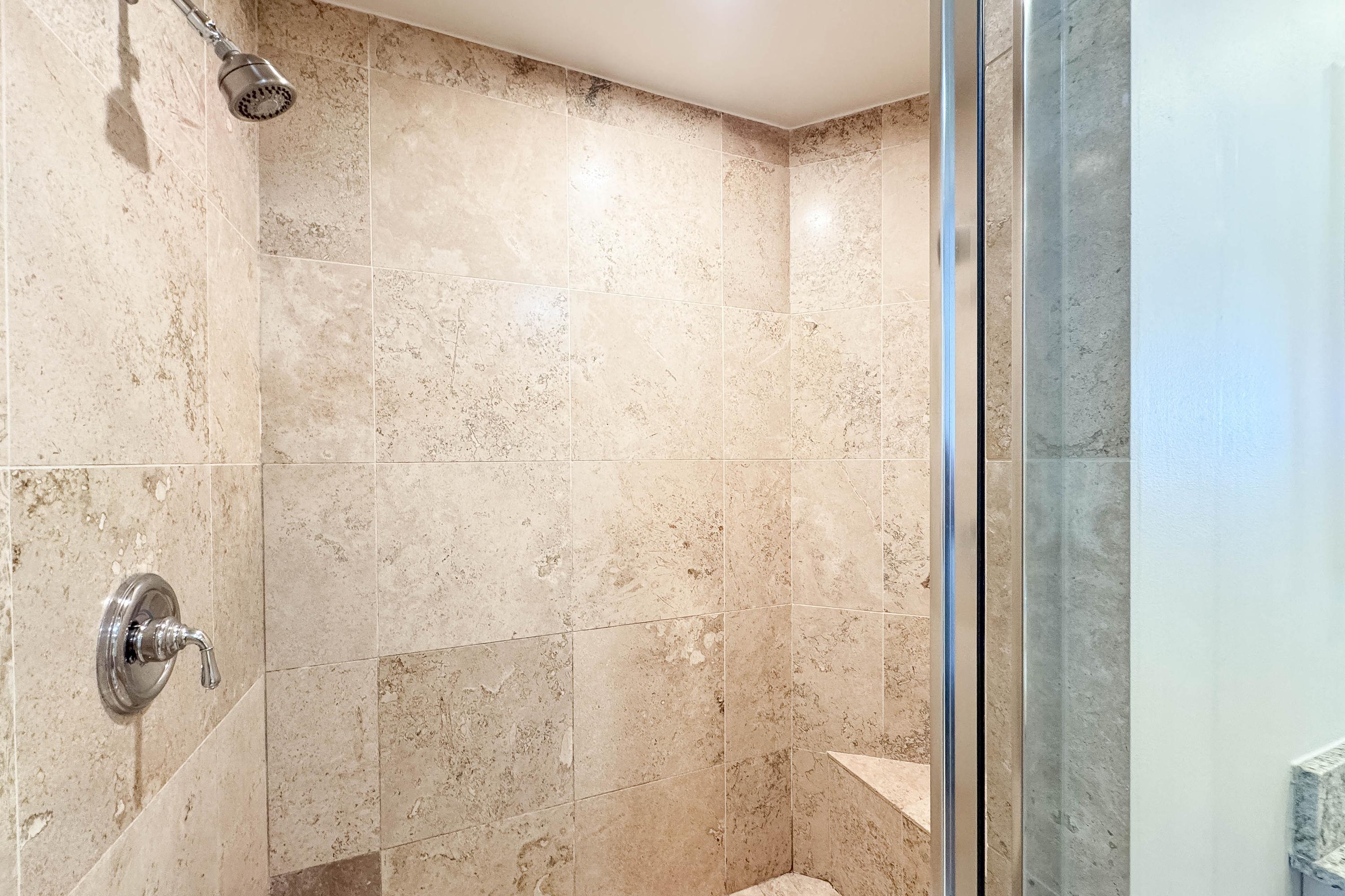 Large, luxurious Travertine walk-in shower with seating bench.