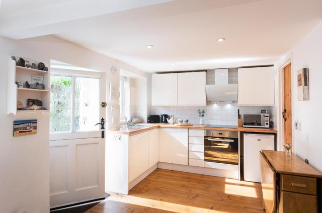 Contemporary fitted kitchen and fold away dining and chairs for four with glass stable door to garden