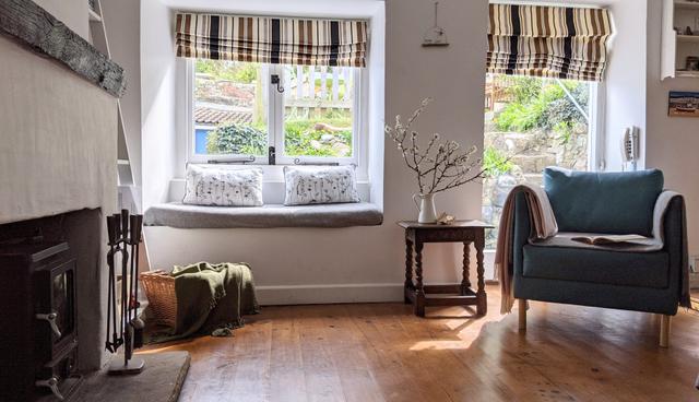 Double windows and window seat with views to garden of the living room  with easy chair and log burner
