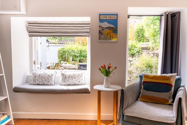 Double windows and window seat with views to garden of the living room  with easy chair and log burner