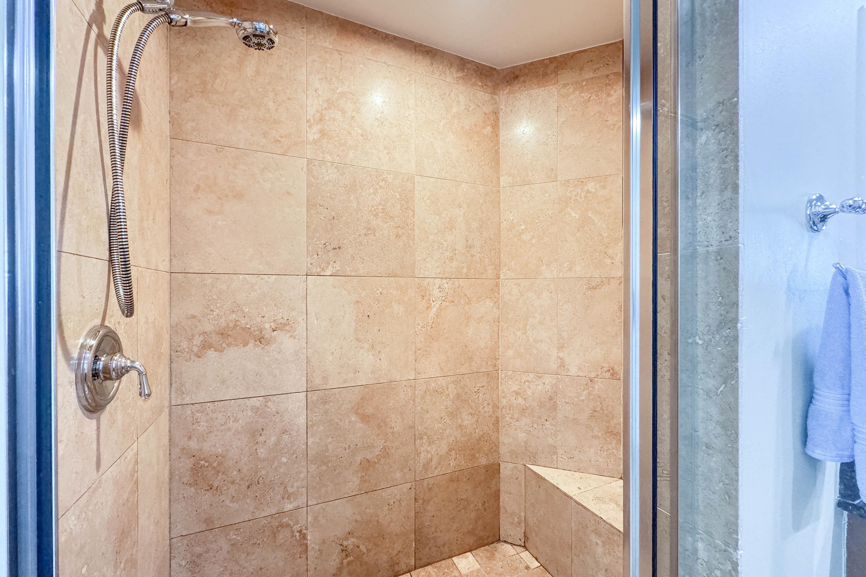 Large, luxurious Travertine walk-in shower with seating bench.