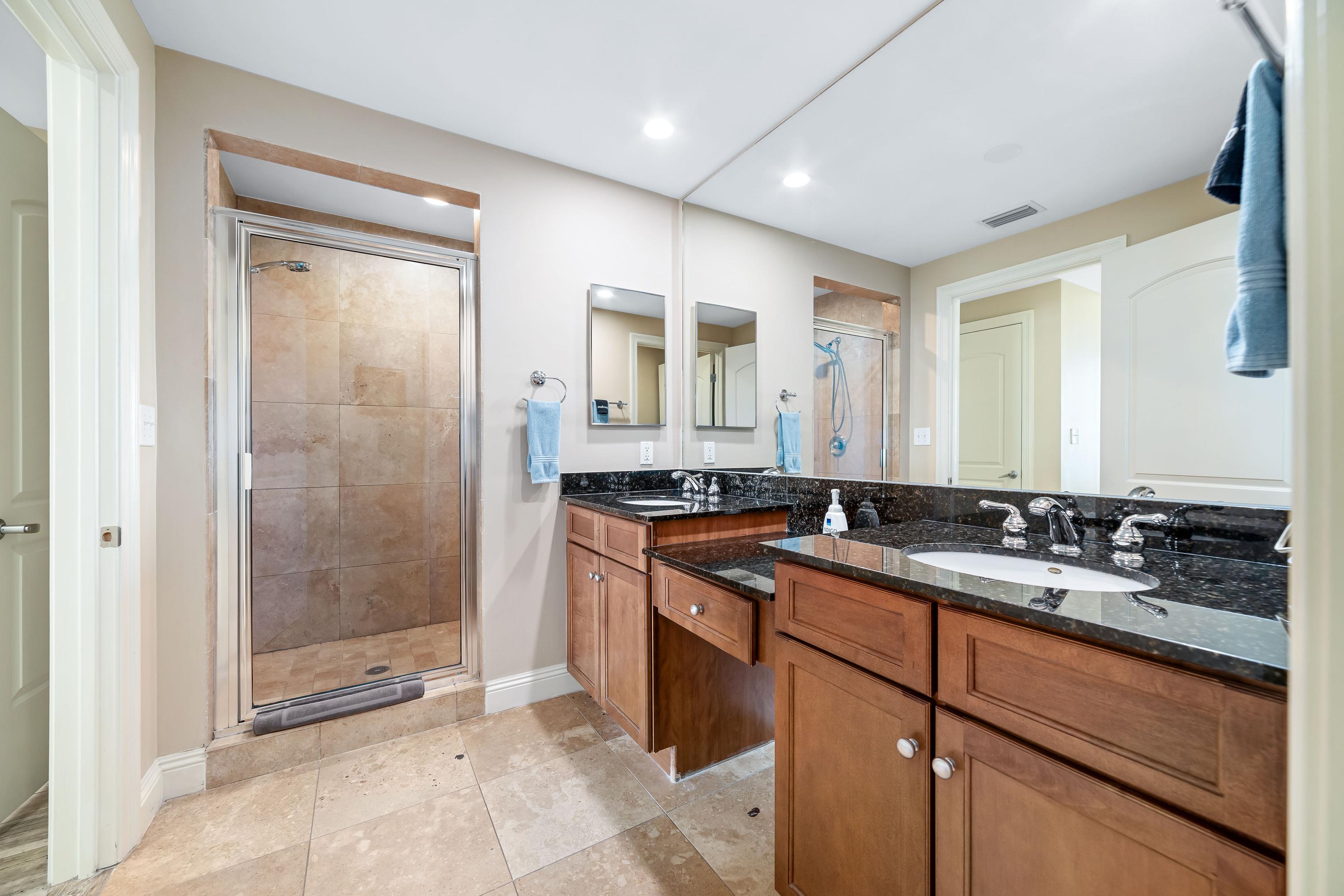 Spacious master bathroom with dual granite vanities, walk-in Travertine shower