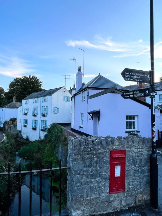 Evening view of exterior of Lym Leat Cottage showing the river Lym 