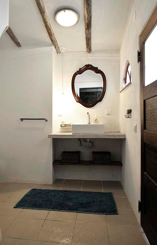 well lit bathroom with round mirror and fancy sink
