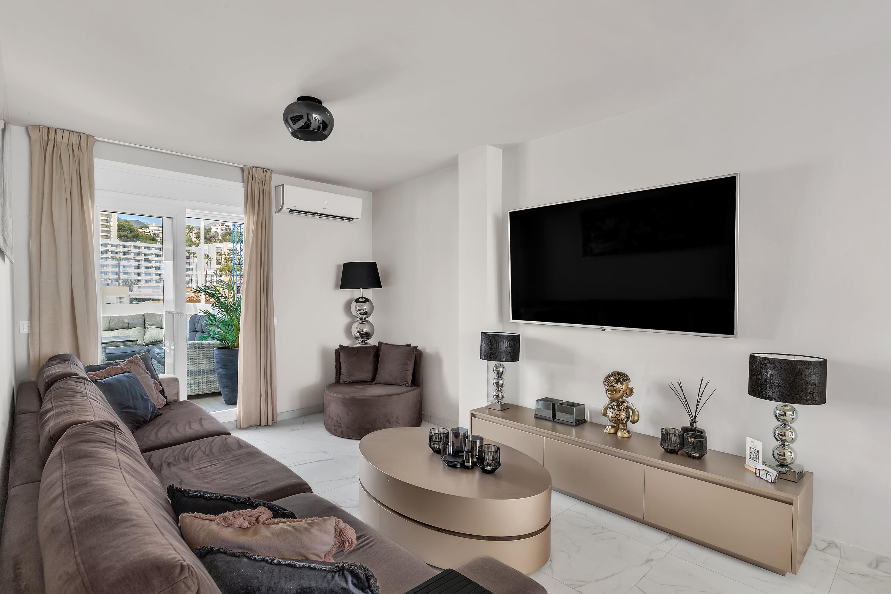 Ruime en verfijnde woonkamer, voorzien van een 65-inch tv en uitzicht op de zee